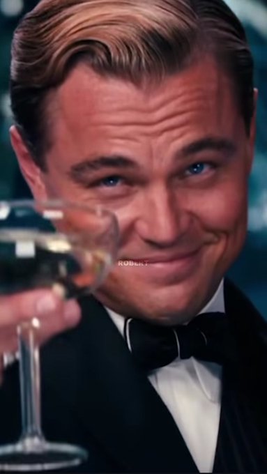 A close-up portrait of Leonardo DiCaprio in a tuxedo holding up a martini glass with a knowing smile, with a faint "ROBART" watermark visible.