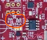 A close-up photograph of a red printed circuit board (PCB) with electronic components, resistors, and integrated circuits, with one area circled in orange.