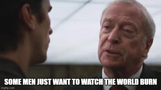 The image shows a man wearing a suit talking to another person who is also dressed in a suit. The text above them reads "Some men just want to watch the world burn", which seems to be a quote from a movie or TV show.