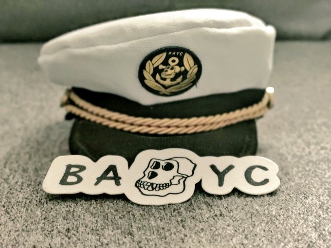 The image features a white sailor's cap with gold accents, placed on its side against a gray background. Below the cap, there are two stickers - one reading "BAYC" and another saying "where is your hat?". The caption suggests that someone has created this image as part of a creative project or challenge related to hats and maritime themes.