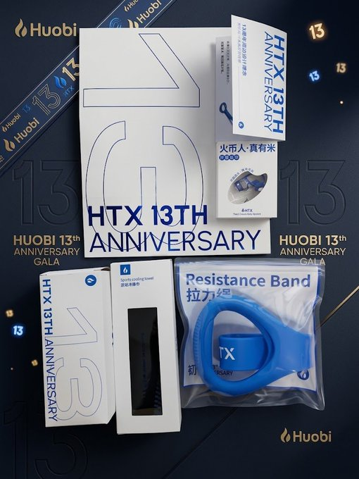 The image showcases a collection of HTX 13th Anniversary promotional merchandise, including a white package labeled "HTX 13th ANNIVERSARY," a "Resistance Band 拉力绳" (in HTX blue), a massage tool (滚珠按摩锤), and a token collectible featuring "13 ANNIVERSARY" and "火币人·真有米" (Huobi People Really Have Rice), all arranged against a dark blue backdrop with "HUOBI 13th ANNIVERSARY GALA" branding and the Huobi flame logo.