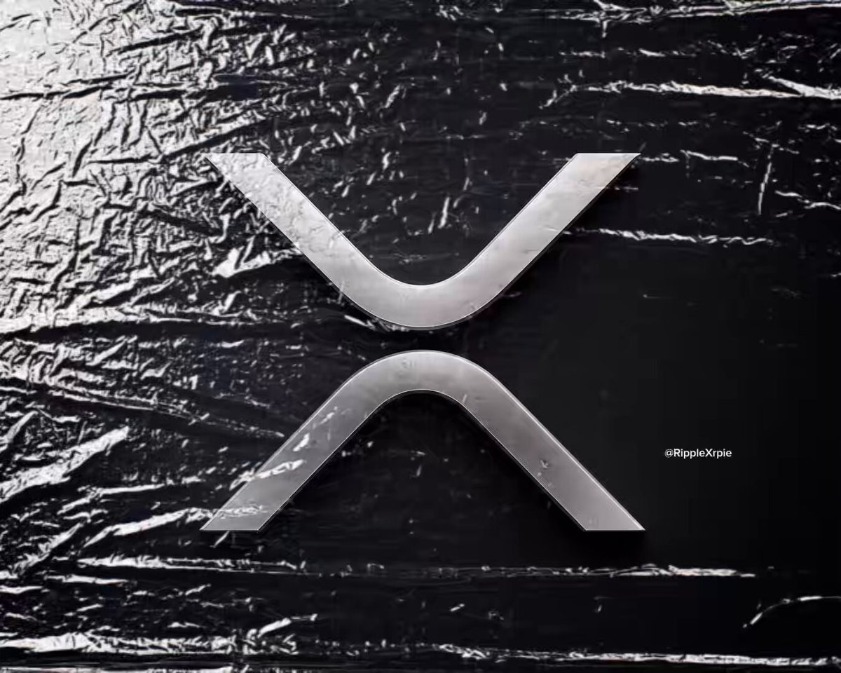 The image features a silver logo with an X shape, which appears to be a symbol or brand name. It is placed against a black background, making it stand out prominently. The caption below the image reads "Just hit that like button if you still hold #XRP." This suggests that the image might be related to cryptocurrency or digital currency, as the XRP logo could represent a specific cryptocurrency exchange or payment method.