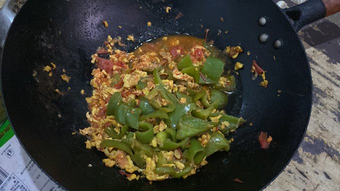 The image shows a black wok filled with food, including green peppers and possibly other ingredients such as tomatoes or onions. The wok appears to be placed on top of a table, suggesting that someone has just finished cooking the dish. The photo is accompanied by text in the caption, which reads "Crypto Survival Plan| Day 14 挑战的第十四天 回家了嘻嘻消费1个多u 炒个菜 @BitgetWalletCN @StellarOrg #StellarPayFiOdyssey #U卡". This post seems to be related to a cryptocurrency project, as indicated by the use of the hashtag.