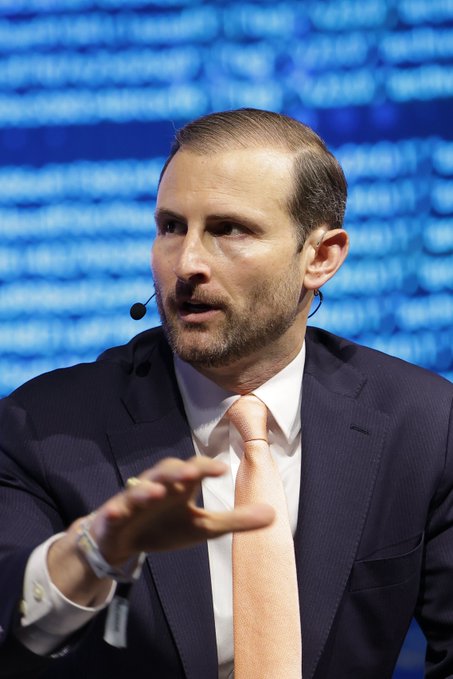 A man in a suit and peach tie, with a microphone near his ear, gestures with his hand. He is likely the White House Executive Director mentioned in the post, suggesting his comments are anticipating new support for a bill.