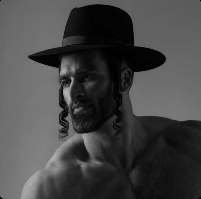 A black-and-white portrait of a shirtless bearded man wearing a black fedora with curled sidelocks (payot).