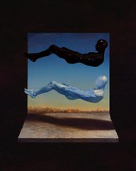 A small photograph held by fingertips against a black background, depicting a person in a blue bodysuit seemingly floating horizontally above a desert landscape, with a dark shape above them.