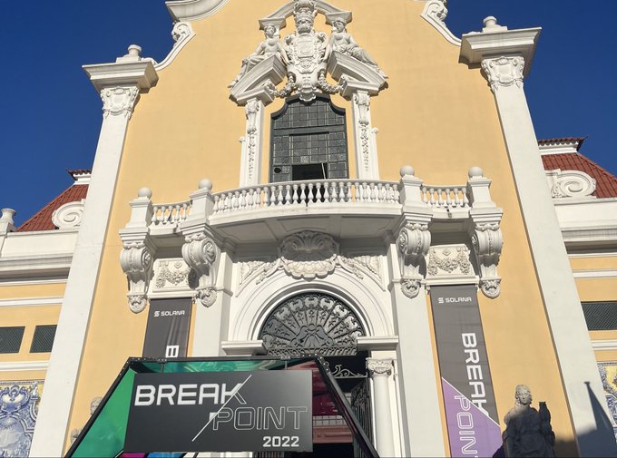 An ornate yellow building facade with elaborate white architectural details and banners for 'BREAK POINT 2022' by SOLANA.