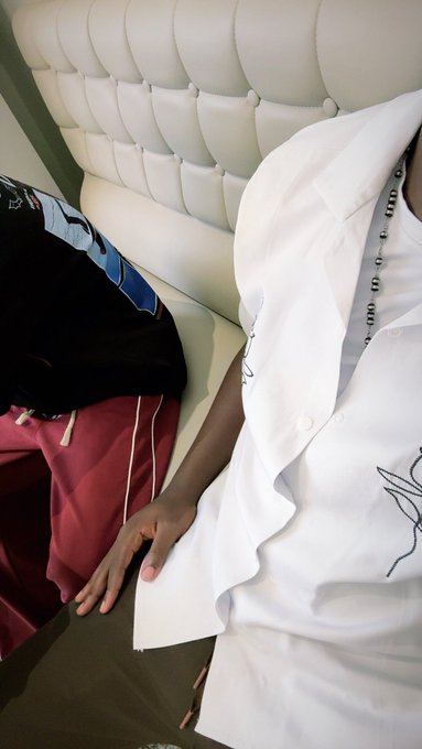 A person wearing a white shirt rests their hand on a tufted white couch, accompanied by a black garment and red drawstring pants nearby. The "gm ct Stay blessed" caption suggests a relaxed, grateful morning greeting, fitting the calm, casual scene.