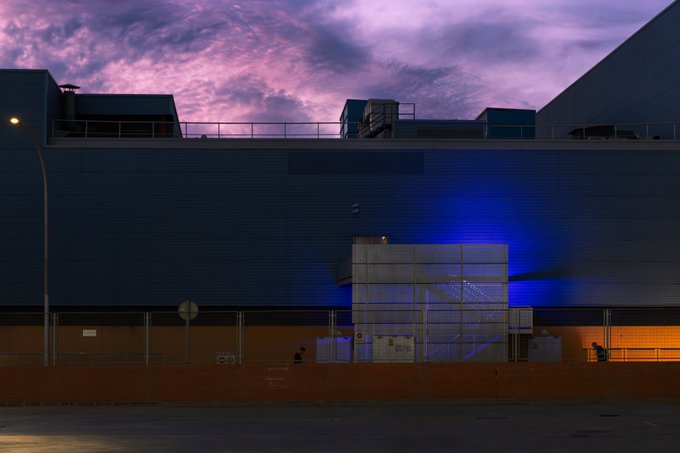 iced blue and purple sky, orange building with white roof, and a large gray structure on the right side of the frame.