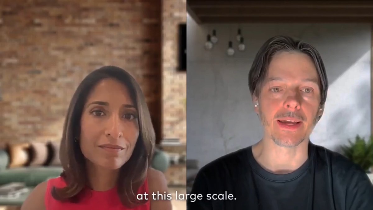 A split-screen video call between two people, with a woman on the left against a brick wall and a man on the right in a modern room, accompanied by the caption "at this large scale." The conversation centers on private credit—a $2T+ market—with discussion about how moving lending onto faster, low-cost rails can expand access and reduce capital costs for underserved global markets.