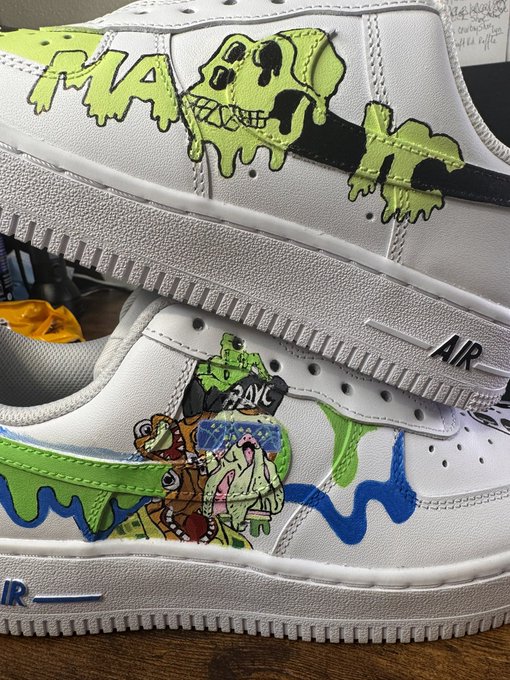 A pair of customized white Nike Air Force 1 sneakers featuring hand-painted green and blue drip designs with cartoon characters, including one wearing a black cap labeled "2AYC."