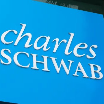 The image shows the Charles Schwab logo in white lettering on a bright blue background. This visual ties directly to the breaking news that Charles Schwab, a $13 trillion financial institution, is now allowing eligible clients to trade Bitcoin and Ethereum alongside traditional stocks.