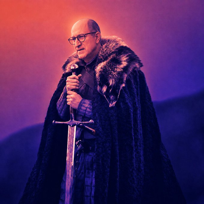 A bald man with glasses, wearing a fur-collared black cloak, grips a sword against a dramatic purple and orange backdrop, evoking the iconic look of Tywin Lannister from Game of Thrones. The post's mention of "STARKtember" hints at anticipation for news of a prequel series, with this image suggesting a Lannister-focused showdown.