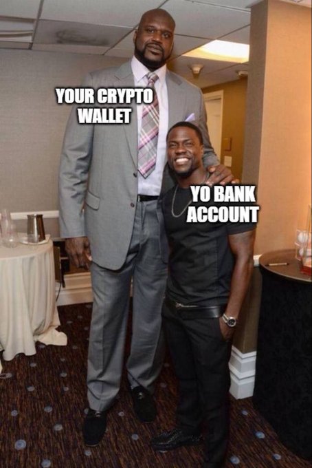 The image is a meme featuring two men of vastly different heights, with the towering figure in a suit labeled "YOUR CRYPTO WALLET" and the much shorter man in a t-shirt labeled "YO BANK ACCOUNT," humorously illustrating the post's message that crypto holdings dwarf traditional bank account balances.