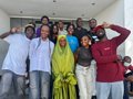A low-resolution group photo of people posing indoors, some making hand gestures.