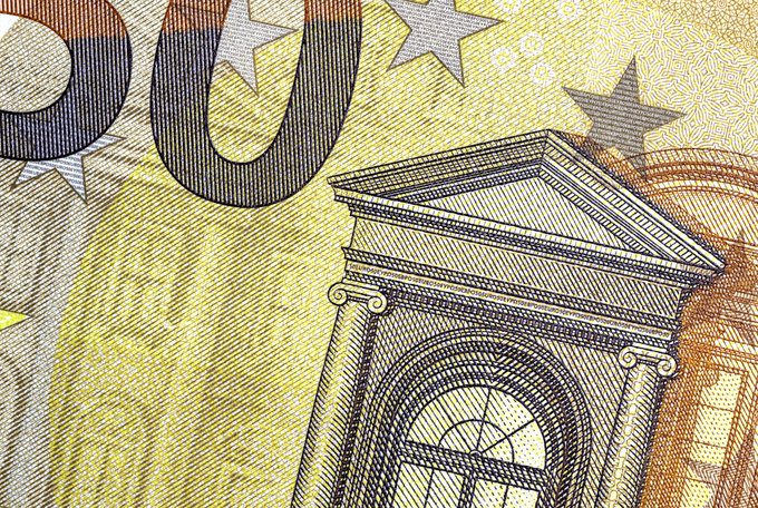 A close-up of a yellow banknote featuring an engraved architectural design with columns and an arched window, along with decorative stars and partial numerals.