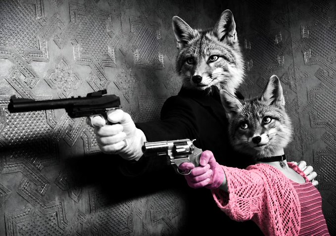 Two figures with fox heads—one larger in a dark suit holding a silenced pistol, and a smaller one in a pink sweater holding a revolver—pose in a dramatic noir-style photograph. The image serves as the artwork "On Léon" being sold via the Objkt NFT marketplace.