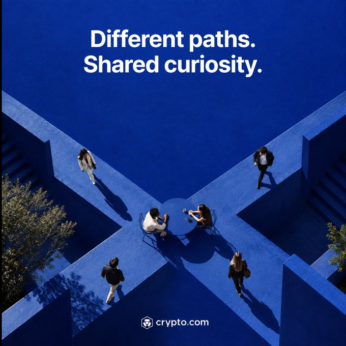 A striking blue-toned image shows people walking along intersecting pathways that meet at a central circle where two figures sit facing each other, with the tagline "Different paths. Shared curiosity." and the "crypto.com" logo at the bottom—visually reinforcing the post's message of diverse individuals converging toward a common "onchain future."