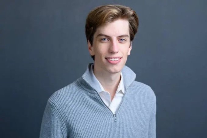 The image features a young man wearing a blue sweater with a white collar, smiling at the camera. The caption below the photo reads "Leopold Aschenbrenner's $IREN position is now up over 8x since he opened it last year." This statement suggests that the photo was taken during the time when Leopold Aschenbrenner received his $IREN award, which indicates a connection to the post.

The image also includes text about the current position of the $IREN award and the age at which it was awarded. The caption provides context for the photograph's subject matter and adds an interesting detail that ties into the overall theme of the post.