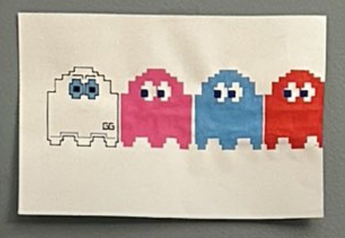 A pixel art drawing on white paper showing four ghost-like figures in a row: one outlined in black with the signature 'GG', and three solid figures in pink, blue, and red.