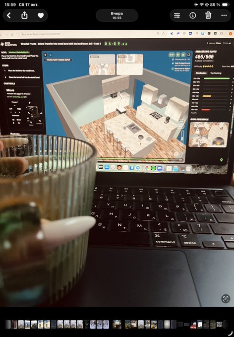 A laptop screen displays a virtual kitchen design program, with a ribbed glass cup in the blurred foreground and the device's keyboard visible below.
