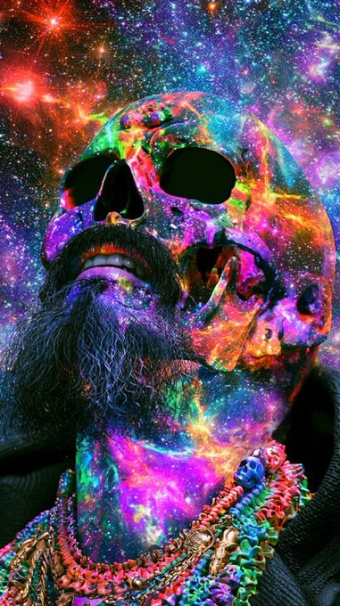 A striking portrait features a bearded man whose face and neck are overlaid with a vivid cosmic galaxy effect, complete with swirling stars, nebulae, and bright bursts of pink, purple, blue, and green light against a deep space background. He wears dark sunglasses and colorful beaded necklaces, creating an otherworldly, psychedelic aesthetic.