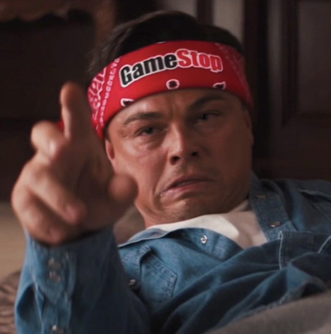 A man wearing a red GameStop bandana and a blue denim shirt points his finger forward with a serious expression.