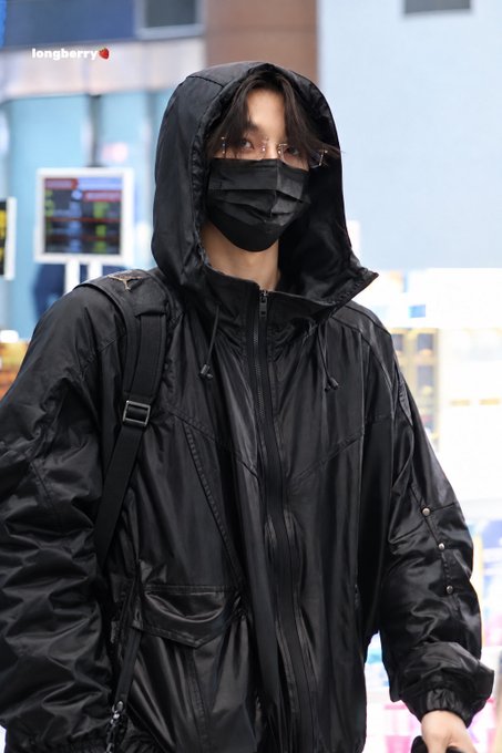 A person in a black hooded jacket and face mask walks through what appears to be an airport terminal, with a "longberry" watermark visible in the upper left corner. The hashtags reference #HeoShinRyong and departure-related tags, suggesting this is a fan-captured photo of the K-pop idol at GMP (Gimpo Airport) on 26/10/19.