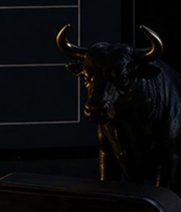 A dark bronze bull statue, reminiscent of Wall Street's iconic charging bull, is dimly lit against a shadowy background, symbolizing bullish market momentum. The accompanying caption, "BINANCE IS HINTING AT A LISTING," suggests the exchange is teasing an upcoming asset listing, with the bull representing optimistic speculation among traders.