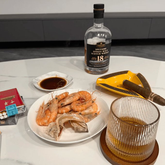 A Speyside 18-year single malt Scotch whisky sits alongside a plate of shrimp and squid with dipping sauce, a glass of whisky, and a cigar, suggesting a scene of indulgent relaxation rather than the serious crypto trading strategy described in the accompanying post. The luxurious spread visually clashes with the text's claims about turning 30,000 into 300,000 through a "Rolling Position Nuclear Bomb Formula," a common tactic in "rags-to-riches" crypto schemes that often use images of wealth to lure investors.
