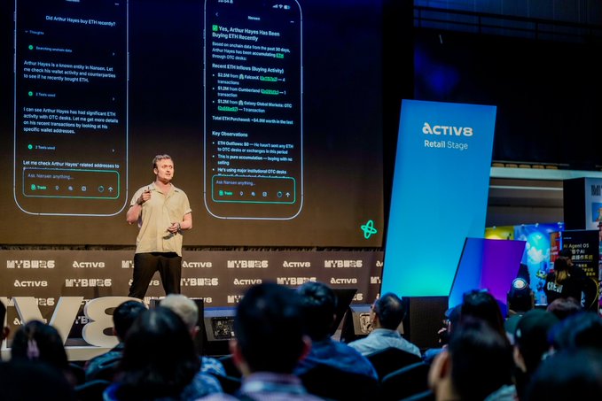 A man speaks on stage at a conference called "ACTIVE Retail Stage," with large screens displaying conversations about ETH rewards and AI.Defi.