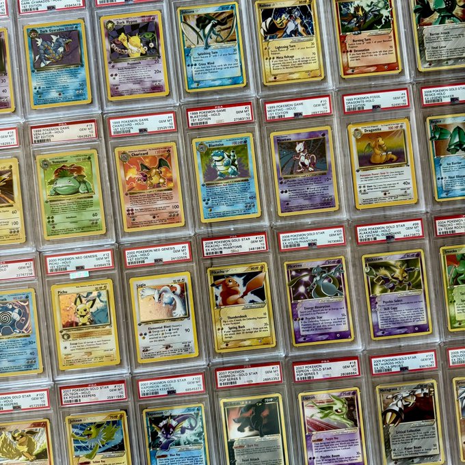 Rows of graded Pokémon trading cards in PSA slabs are displayed, featuring holographic rare cards such as Pikachu, Charizard, Blastoise, and Dragonite with high Gem Mint ratings of 10 (e.g., 27381255, 26839767). The collection showcase perfectly matches the caption "I like shiny cardboard," highlighting the prized holographic finishes and pristine condition of these collectible cards.