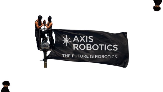 Two workers in hard hats stand on a cherry picker unveiling a black flag that reads 'AXIS ROBOTICS - THE FUTURE IS ROBOTICS'.