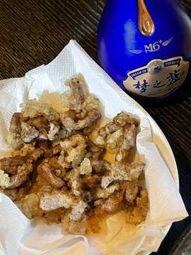 A basket of golden-brown fried food (appears to be karaage or fried chicken pieces) sits on a paper-lined plate next to a blue bottle labeled 'M6 梦之蓝' (Meng Zhi Lan).