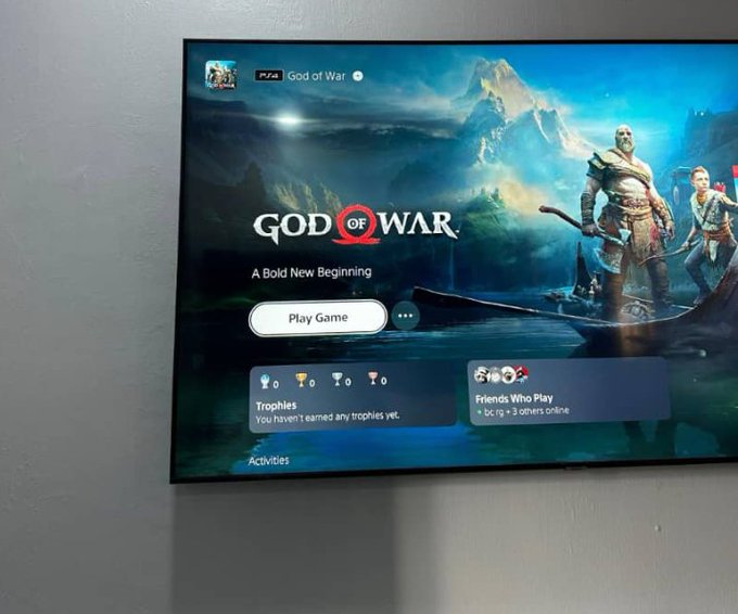 A television screen displaying the PlayStation game menu for 'God of War' with the subtitle 'A Bold New Beginning' and a 'Play Game' button.