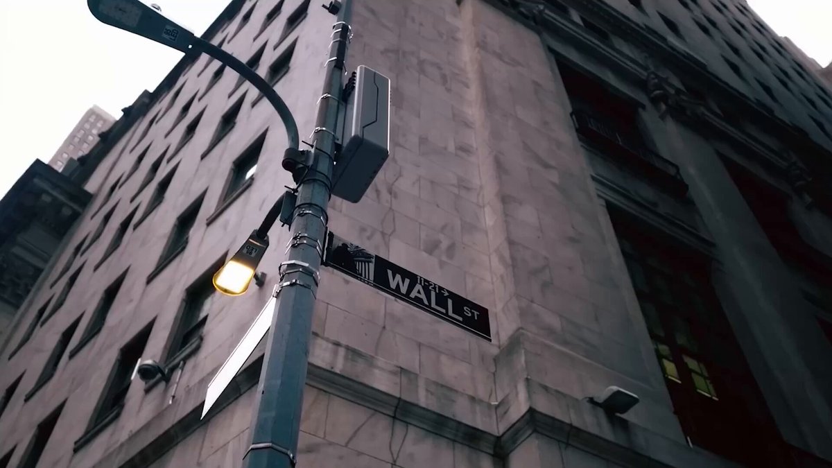The image shows a street sign for Wall Street, with a tall building nearby. The perspective of the photo is from below, looking up at the sign and the building. The text on the image reads "It can only happen if you're here. A new client A new idea A new partnership A new employee A new career Avalanche Summit New York is where we all meet and move the industry forward. Together. Info & tickets".