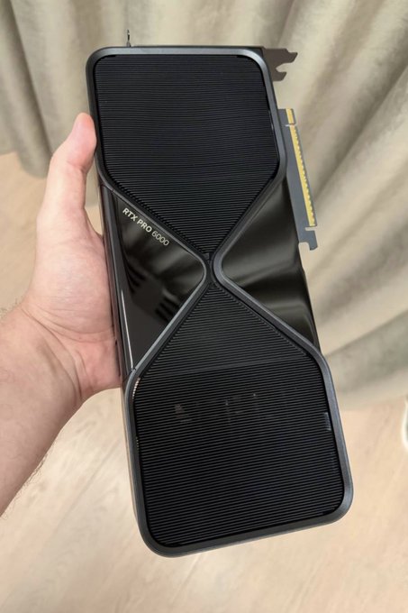 A hand holds an NVIDIA RTX PRO 6000 graphics card, with its distinctive black geometric shroud and gold PCIe connector visible, alongside the "RTX PRO 6000" branding etched on the side—showcasing the new 96GB VRAM workstation GPU destined for Crynux.io's decentralized compute network.