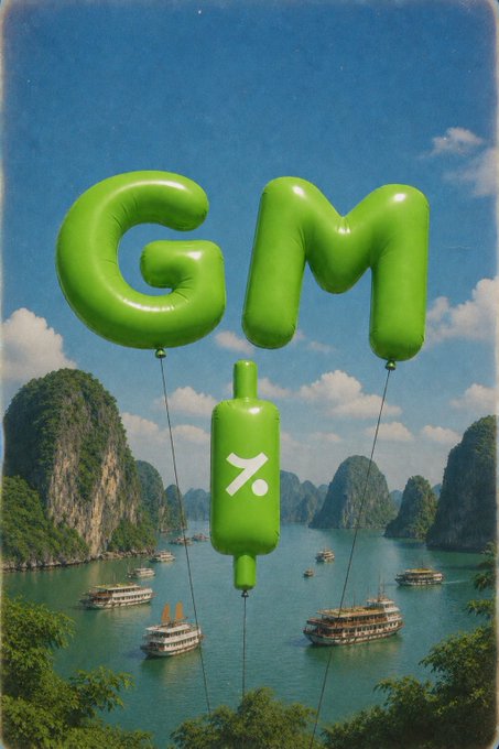 Large green balloon letters spelling 'GM' with a '%' balloon float over a scenic seascape with boats and limestone karst cliffs.
