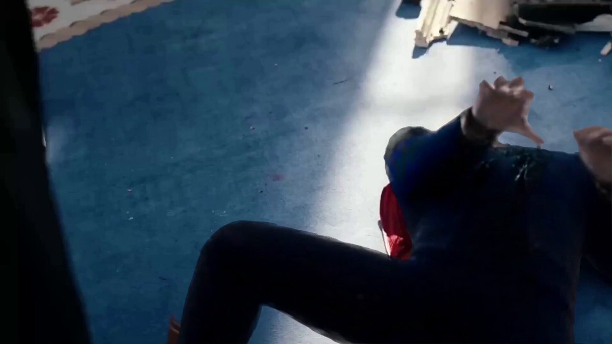 The image shows a person lying down on their stomach, with their arms raised above their head. The background features a blue floor that appears dirty or stained. There are also some pieces of clothing scattered around the room, including a red shirt and a black jacket. The caption reads "please solana please i'm begging you please go back to all time highs i'n't sure what else to do please i'm begging you for the love of god".