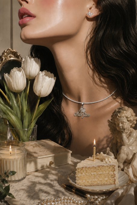 A woman wearing a diamond "Marya" name necklace, stud earrings, and a tennis chain poses beside a birthday cake with a lit candle, surrounded by white tulips, a cherub statue, a vintage mirror, and candles. The personalized "Marya" pendant directly references the artist @marya_art_, visually tying the elegant, romantic scene to her newly collected NFT artwork "Afterlight."