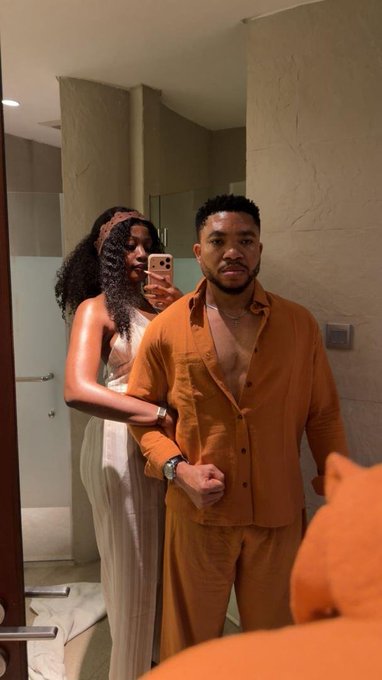 A couple poses together for a mirror selfie in a bathroom, with the woman holding up a phone to capture the shot while the man in an orange button-down stands beside her. The image appears unrelated to the post's text about cryptocurrency chains and blockchain technology, serving simply as a personal photo rather than illustrating the crypto discussion.