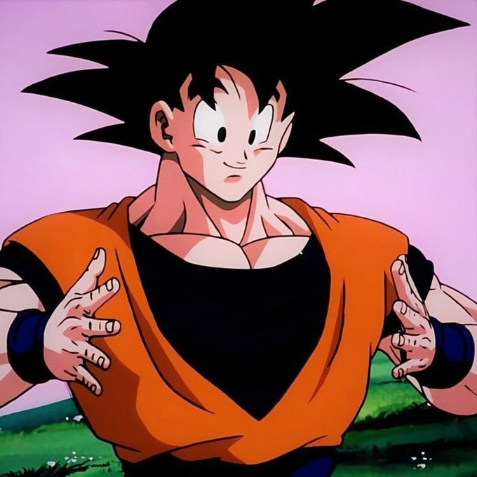 Anime screenshot of Goku from Dragon Ball Z in his classic orange gi and black undershirt, standing outdoors with a serious expression.