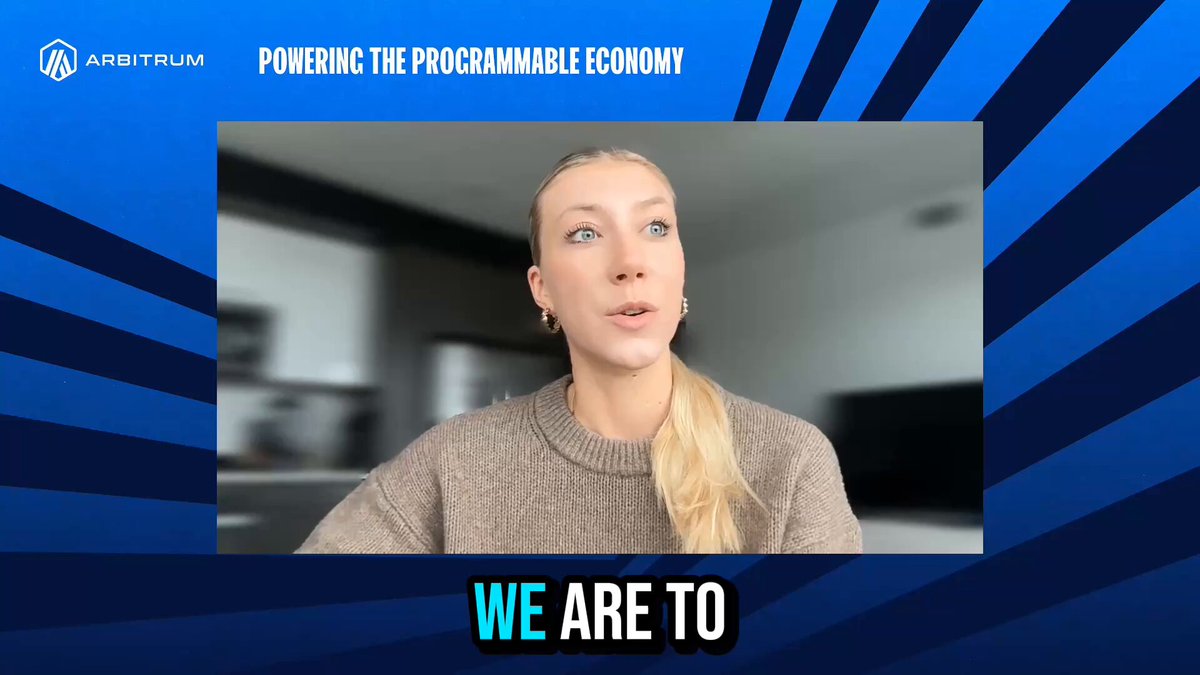 The image features a woman wearing a brown sweater who appears to be giving a presentation or speaking at an event. The background of the image has blue stripes, which adds a vibrant touch to the scene. The caption below the image reads "We Are To", indicating that the woman is addressing her audience on a specific topic related to the post about decentralization and markets.