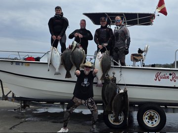 A group of five people pose with several large halibut they caught while standing next to a fishing boat named 'Kristin Re...'