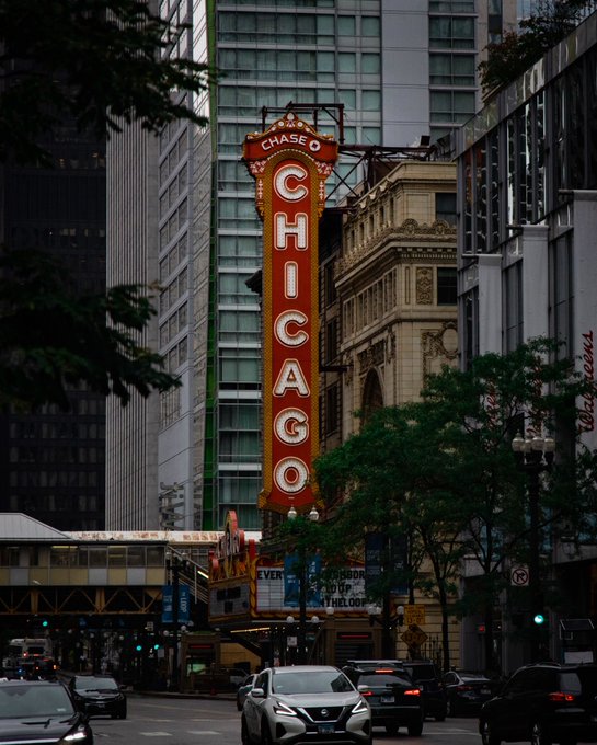 Photograph of a tall red neon sign reading 'CHASE' at the top and 'CHICAGO' vertically down the side, attached to a building in a city street.