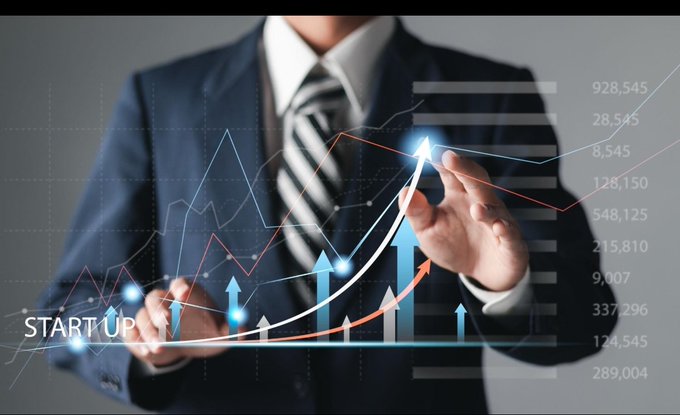 A businessman in a suit points at a glowing upward-trending arrow surrounded by rising bars and line graphs, with the word "STARTUP" and large numerical figures such as 928,545, 548,125, and 337,296 displayed. The image visually reinforces the post's message about BeldexCoin's strong upward growth and high participation metrics, symbolizing the project's evolution from a 2018 Monero fork into a high-performing PoS blockchain with 10,000 BDX masternodes.