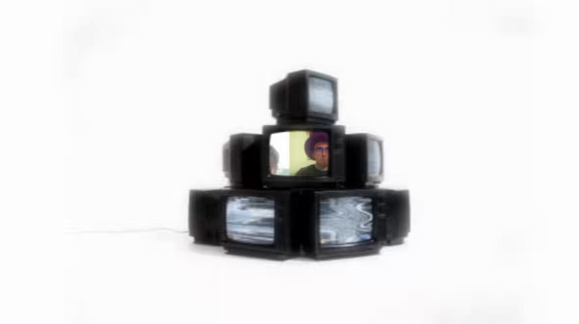 The image features a stack of seven black televisions, each displaying an image of a man's face. The televisions are arranged in a pyramid-like structure, creating a visually striking scene. The caption below the image reads "Degen founder reveals the mindset that keeps him focused long term". This implies that the founder has a strong focus on his work and is determined to succeed despite any obstacles or challenges he may face.