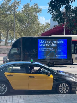 A yellow and black taxi is parked in front of a bus displaying a Ripple Treasury advertisement reading "More settlements. Less settling." promoting Ripple's On-Demand Liquidity and Ripple Treasury at EuroFinance Barcelona, with the Ripio logo visible below.
