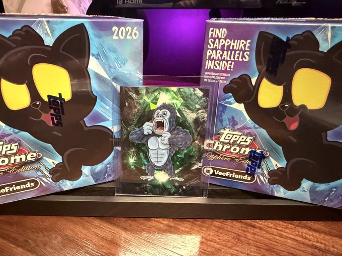 A Topps Chrome Sapphire Edition 2026 trading card box featuring VeeFriends characters, with a 'FIND SAPPHIRE PARALLELS INSIDE!' promotional banner and a graded Donkey Kong card displayed in front.
