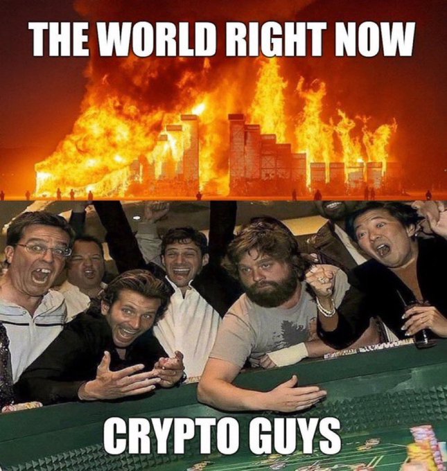 A meme showing men cheering excitedly at a casino table in the foreground, with the casino building engulfed in flames in the background; text reads 'THE WORLD RIGHT NOW' at the top and 'CRYPTO GUYS' at the bottom.